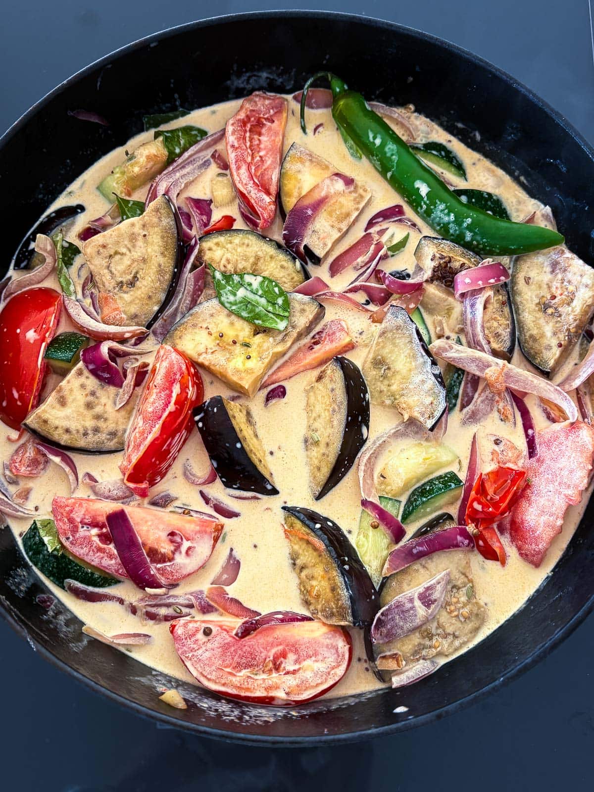 large pot of vegetable curry in coconut tamarind sauce with tomatoes, zucchini, peppers, onions. 