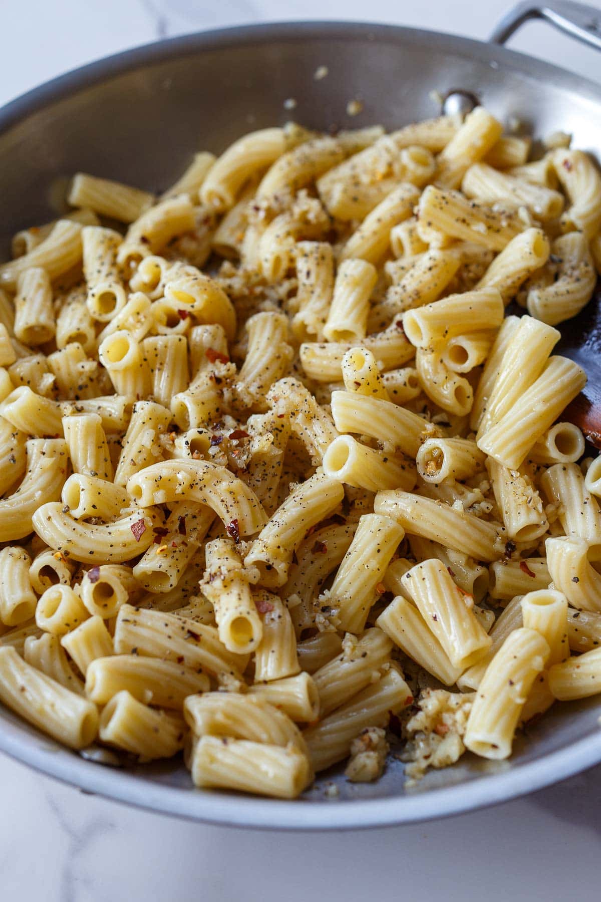 cooked pasta added to sauté pan with garlic and chili flakes. 
