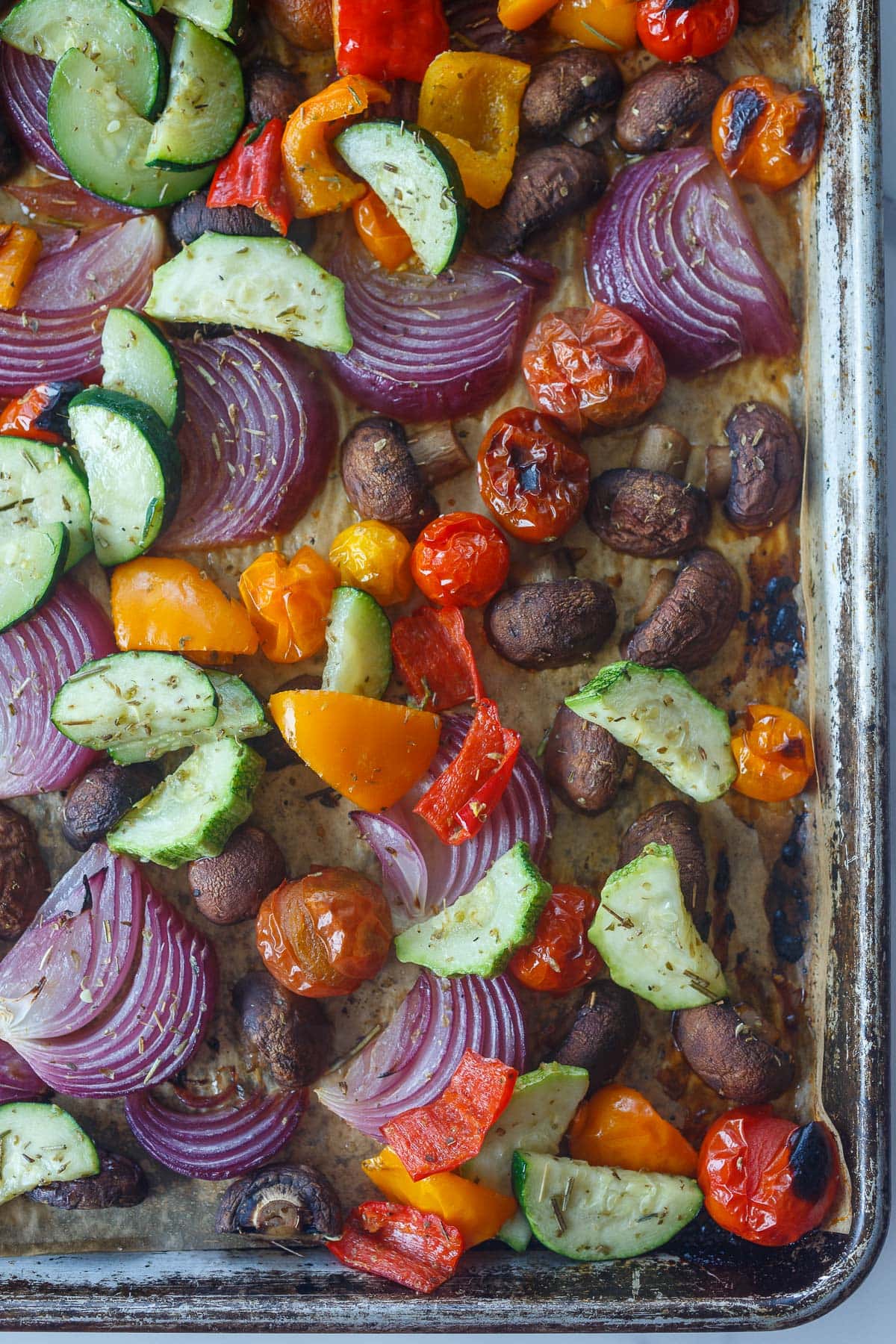 baking sheet with roasted vegetables - zucchini, bell peppers, red onion, mushrooms, and cherry tomatoes. 