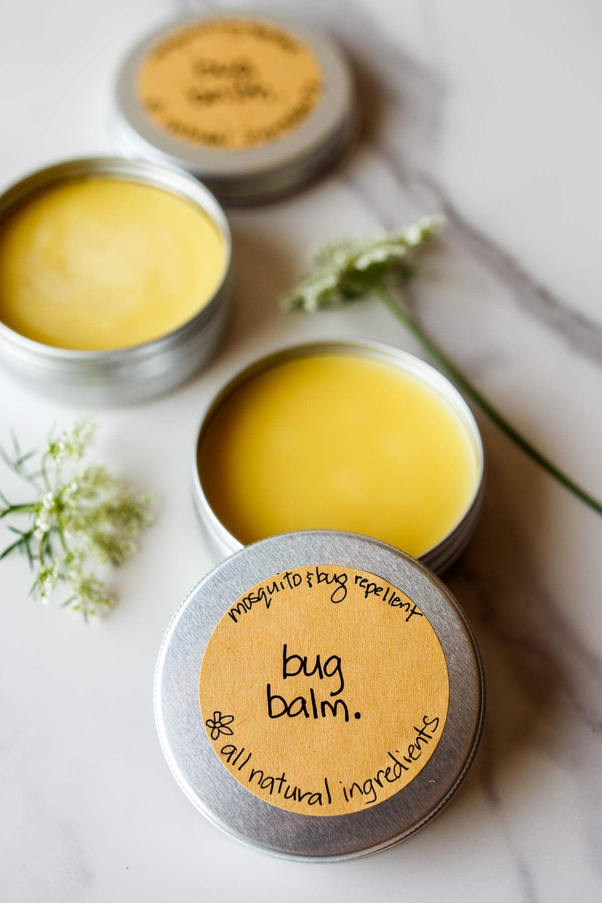 tin of homemade mosquito repellent (bug balm) with a lid with brown sticker that reads "mosquito & bug repellent bug balm all natural ingredients."