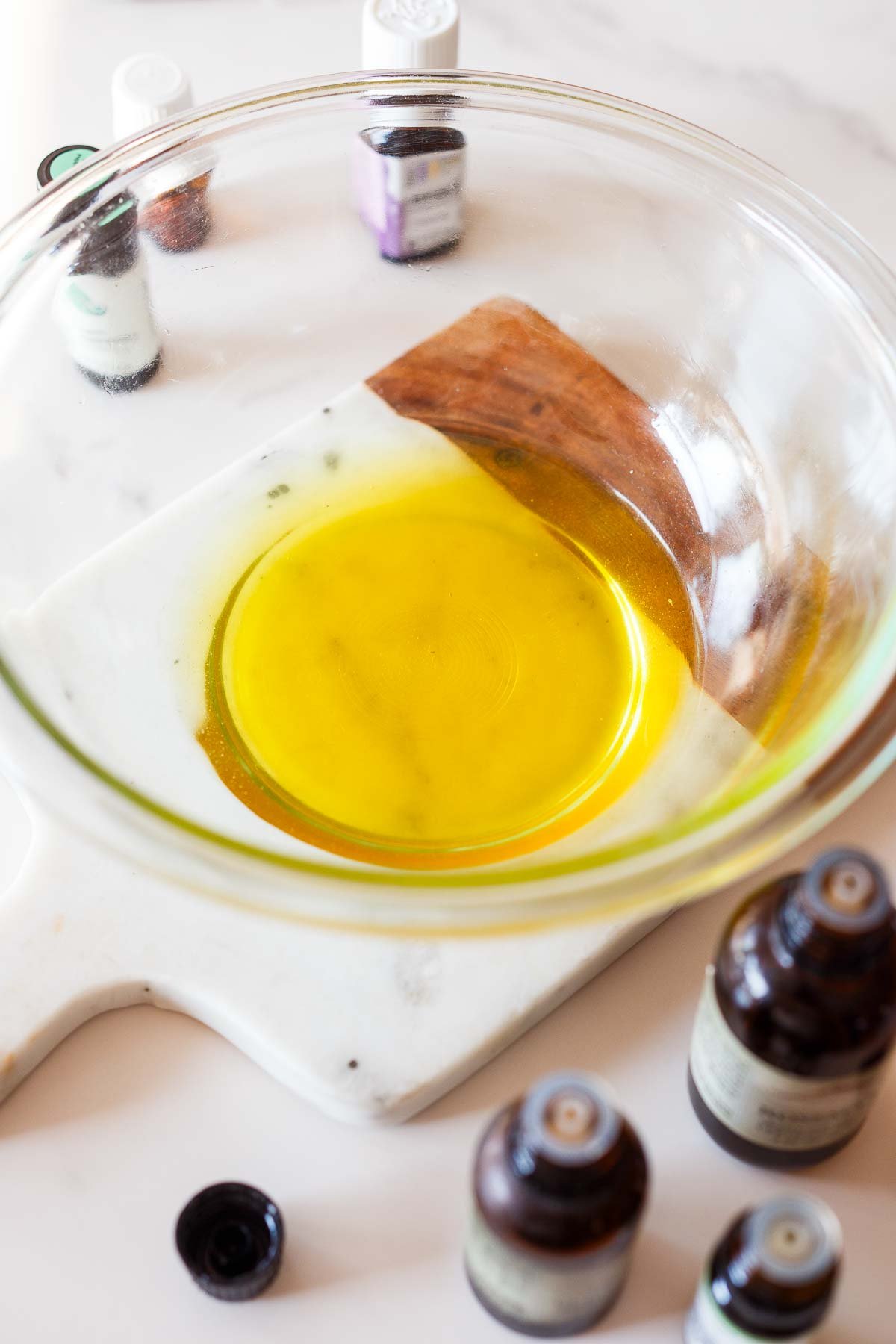 glass bowl of jojoba oil with essential oils and melted beeswax to make a mosquito repellent bug balm. 