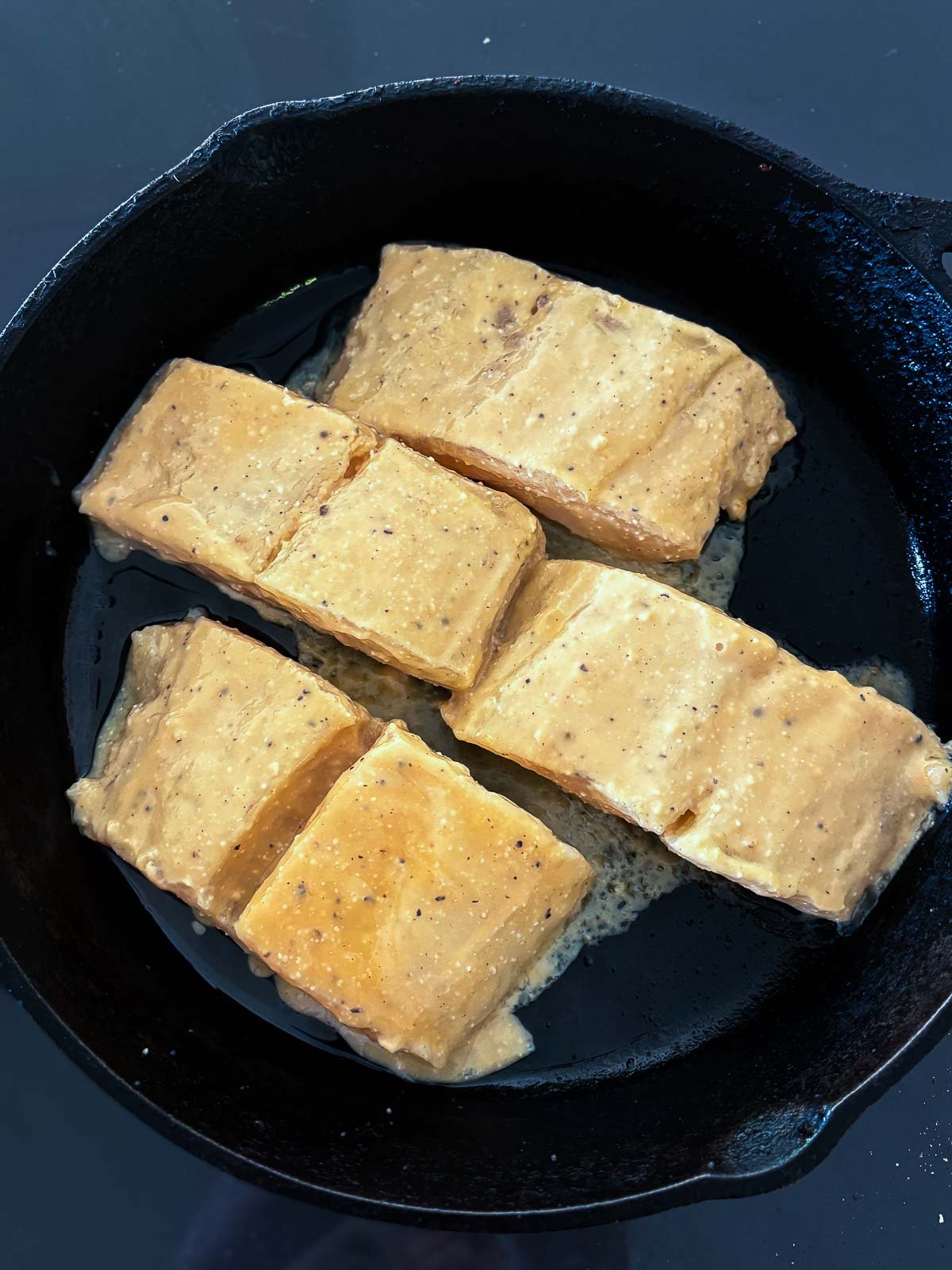 Crisping the skin of the black cod in an oiled skillet. 