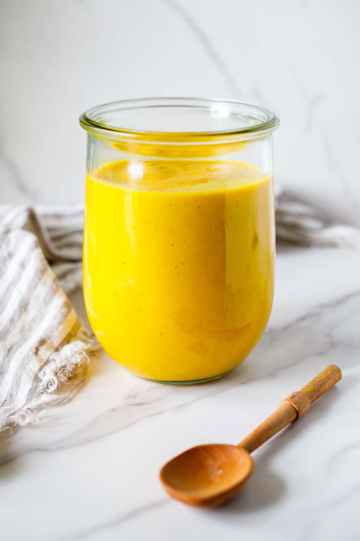 glass jar labeled "butternut sauce" with creamy butternut squash pasta sauce next to wood spoon and sage leaves.