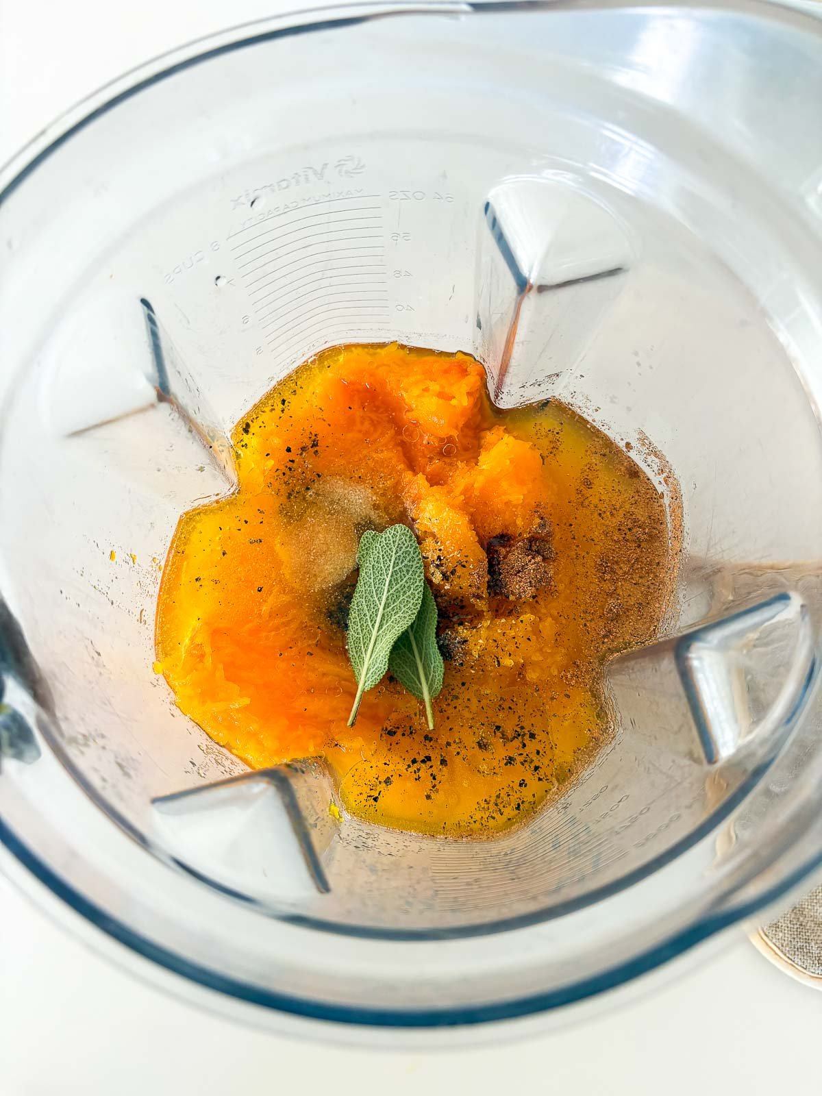 blender with butternut squash flesh, spices, and sage leaves.
