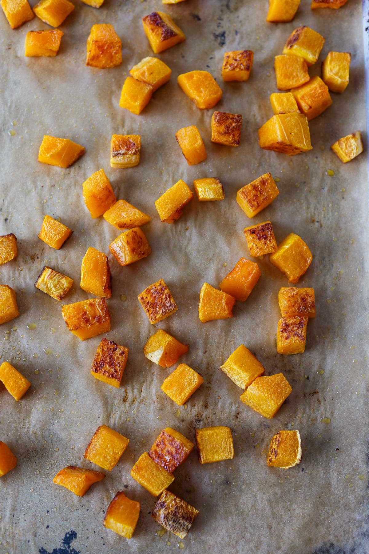 roasted butternut squash cubes on parchment-lined baking sheet.