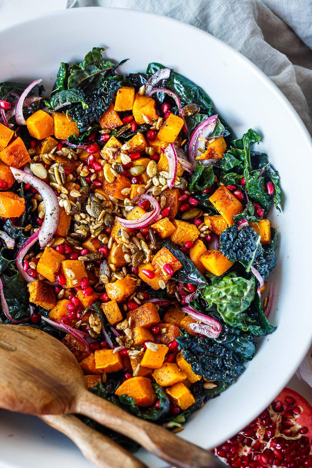 large bowl with butternut squash kale salad with pomegranate, red onion, and seeds.