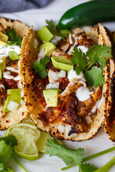 This chef-tested chicken taco recipe is easy and delicious! Made with tender, juicy baked chicken thighs, shredded and piled into warm tortillas.