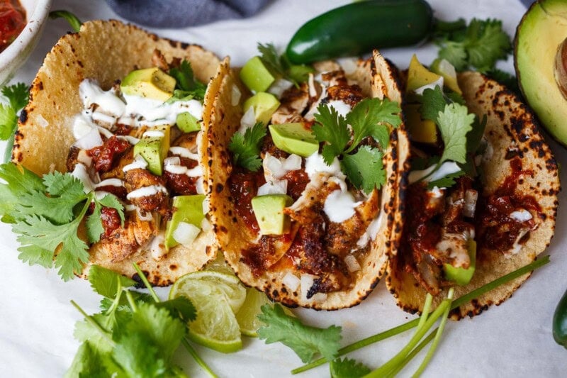 This chef-tested chicken taco recipe is easy and delicious! Made with tender, juicy baked chicken thighs, shredded and piled into warm tortillas.