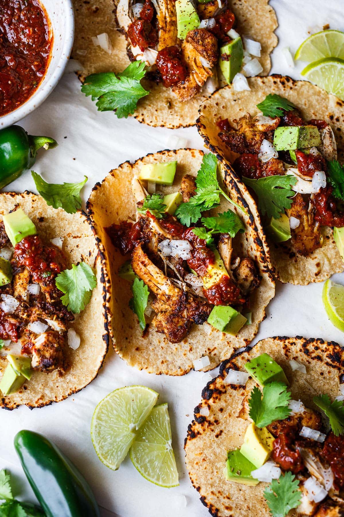 three chicken tacos topped with salsa roja, avocado, white onion, sour cream, cilantro.