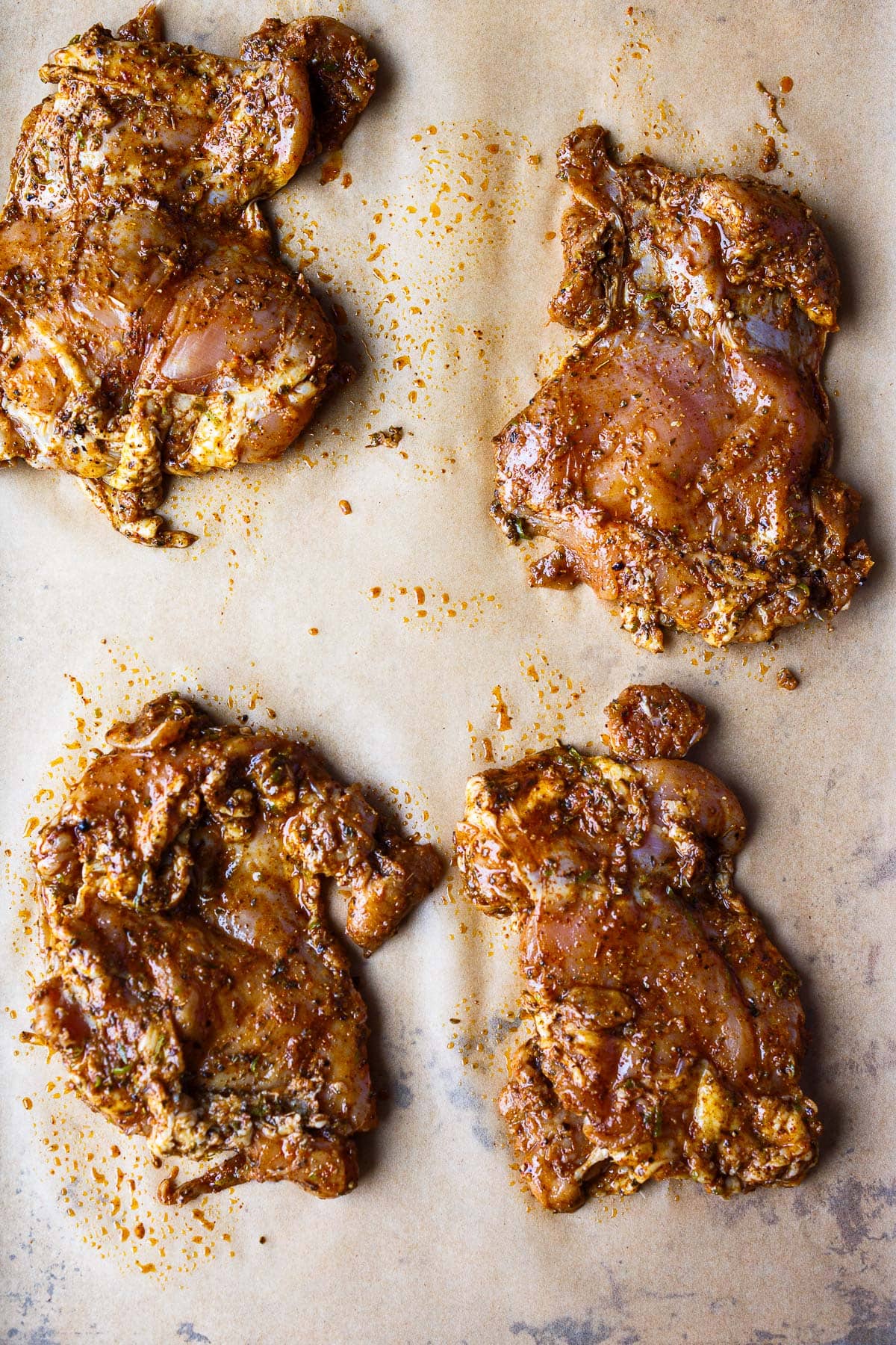 marinated chicken placed on parchment-lined baking sheet.
