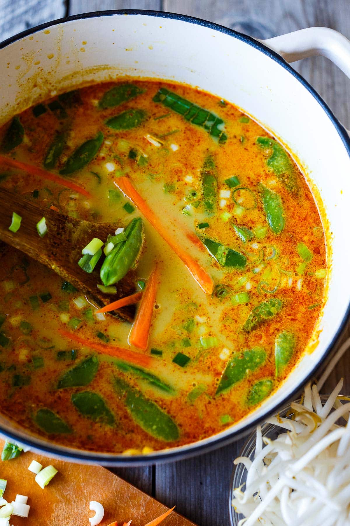 dutch oven with curry ramen broth with carrots, green onions, and snap peas added.