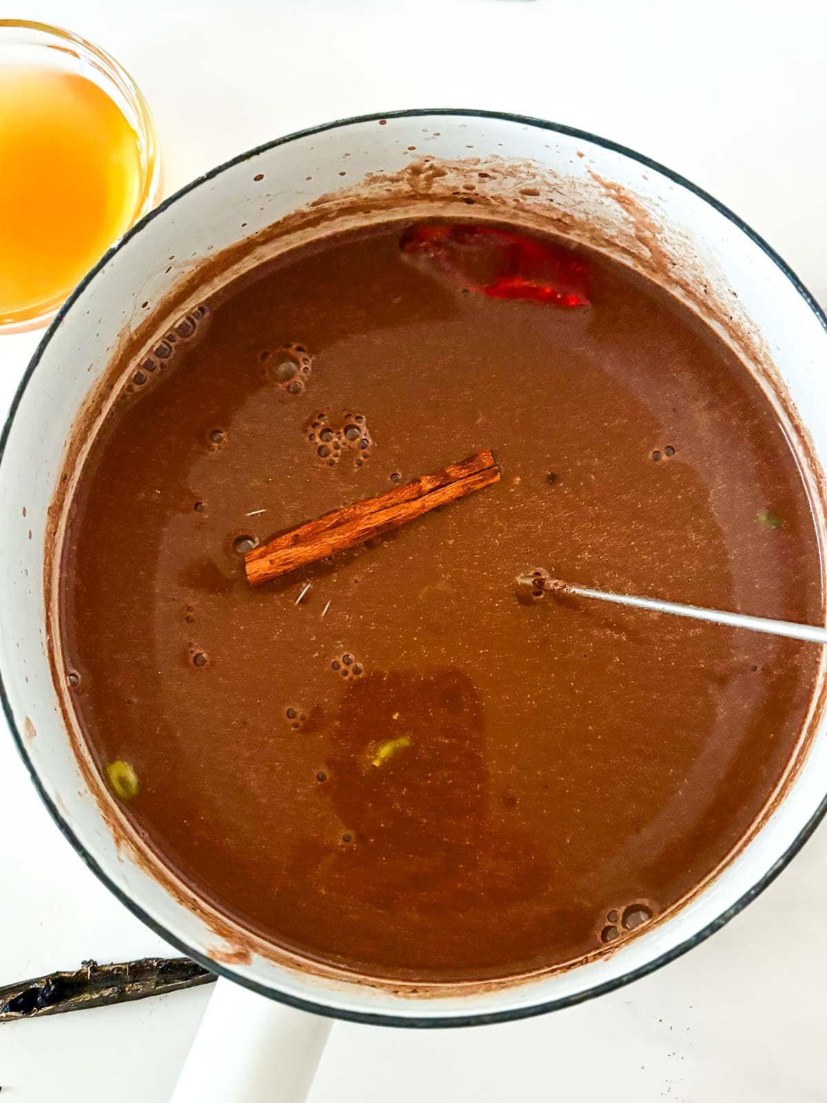 pot with Mexican hot chocolate with a cinnamon stick and dried red chili.