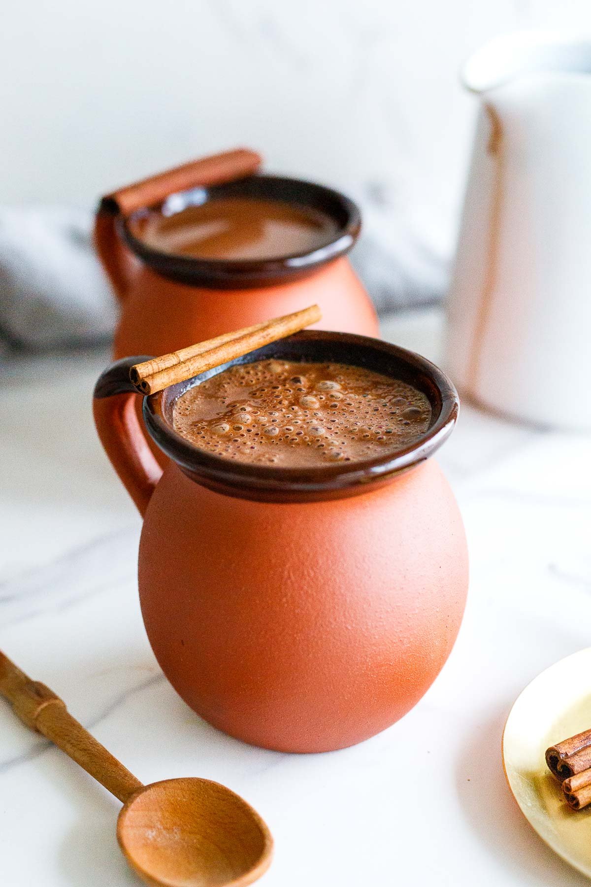 Mexican hot chocolate in mug garnished with cinnamon stick.