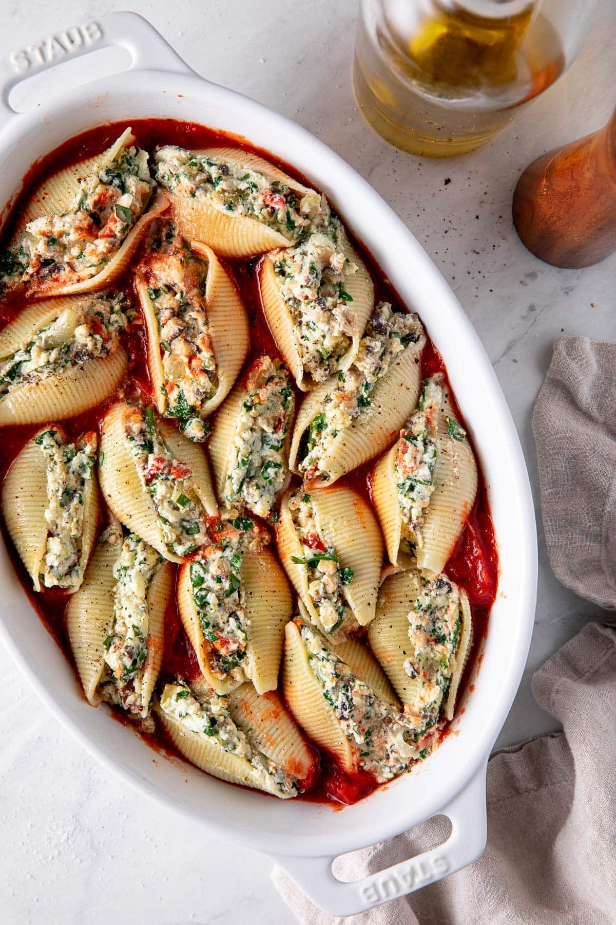 oval baking dish with stuffed shells with ricotta, spinach, veggie filling before being baked.