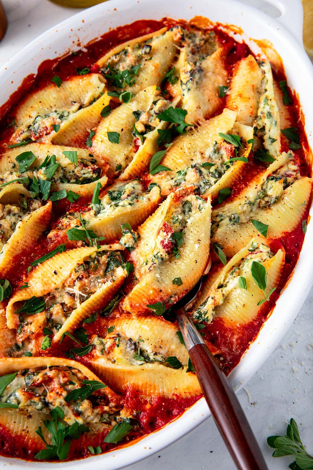 stuffed shells with ricotta, veggies, and spinach, garnished with parsley, placed in marinara sauce.