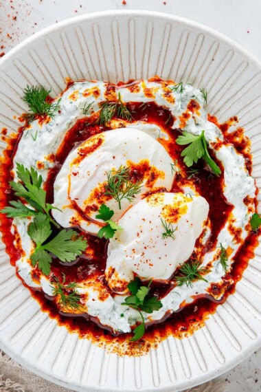 the best turkish poached eggs with herbed yogurt and aleppo butter on a plate.