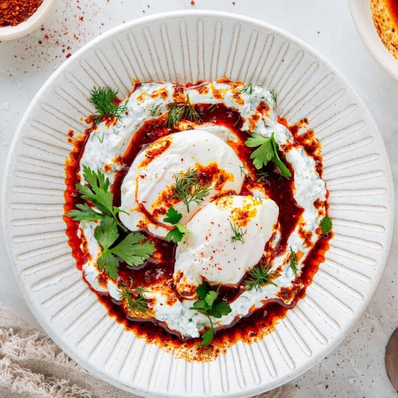 the best turkish poached eggs with herbed yogurt and aleppo butter on a plate.