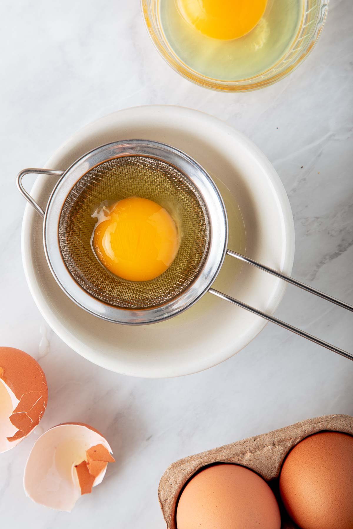 small fine-mesh sieve with egg over small bowl. 
