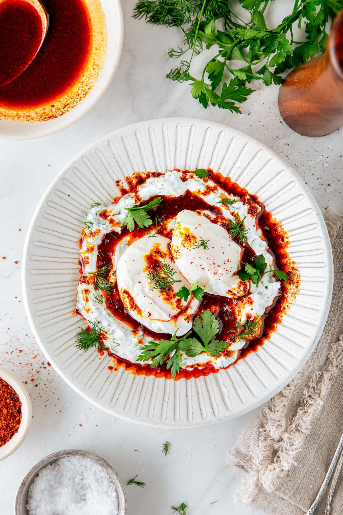 plate of Turkish eggs - poached eggs on herbed yogurt with Aleppo butter and fresh herbs. 