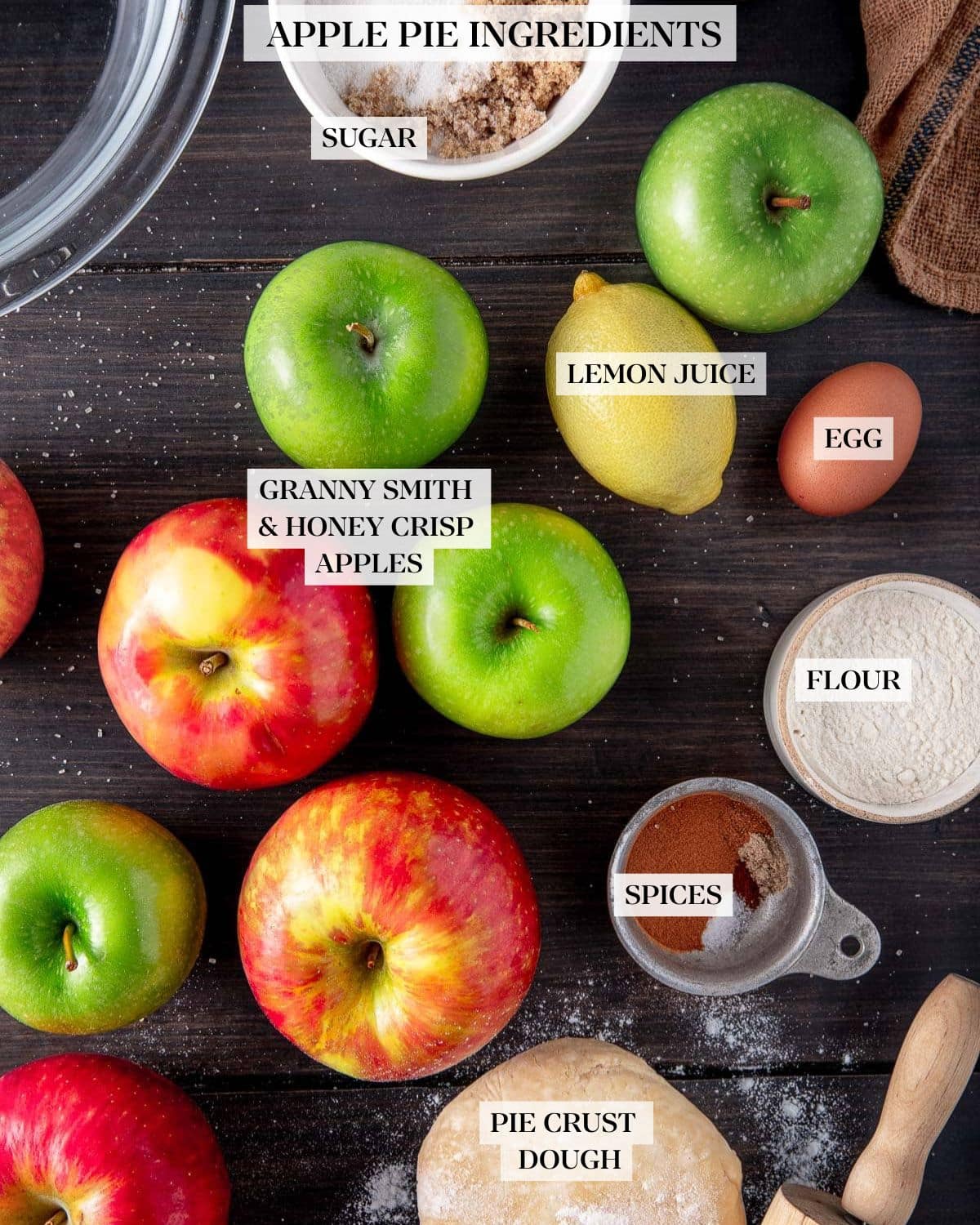 apple pie ingredients - sugar, apples, lemon, egg, flour, spices, pie dough, rolling pin. 