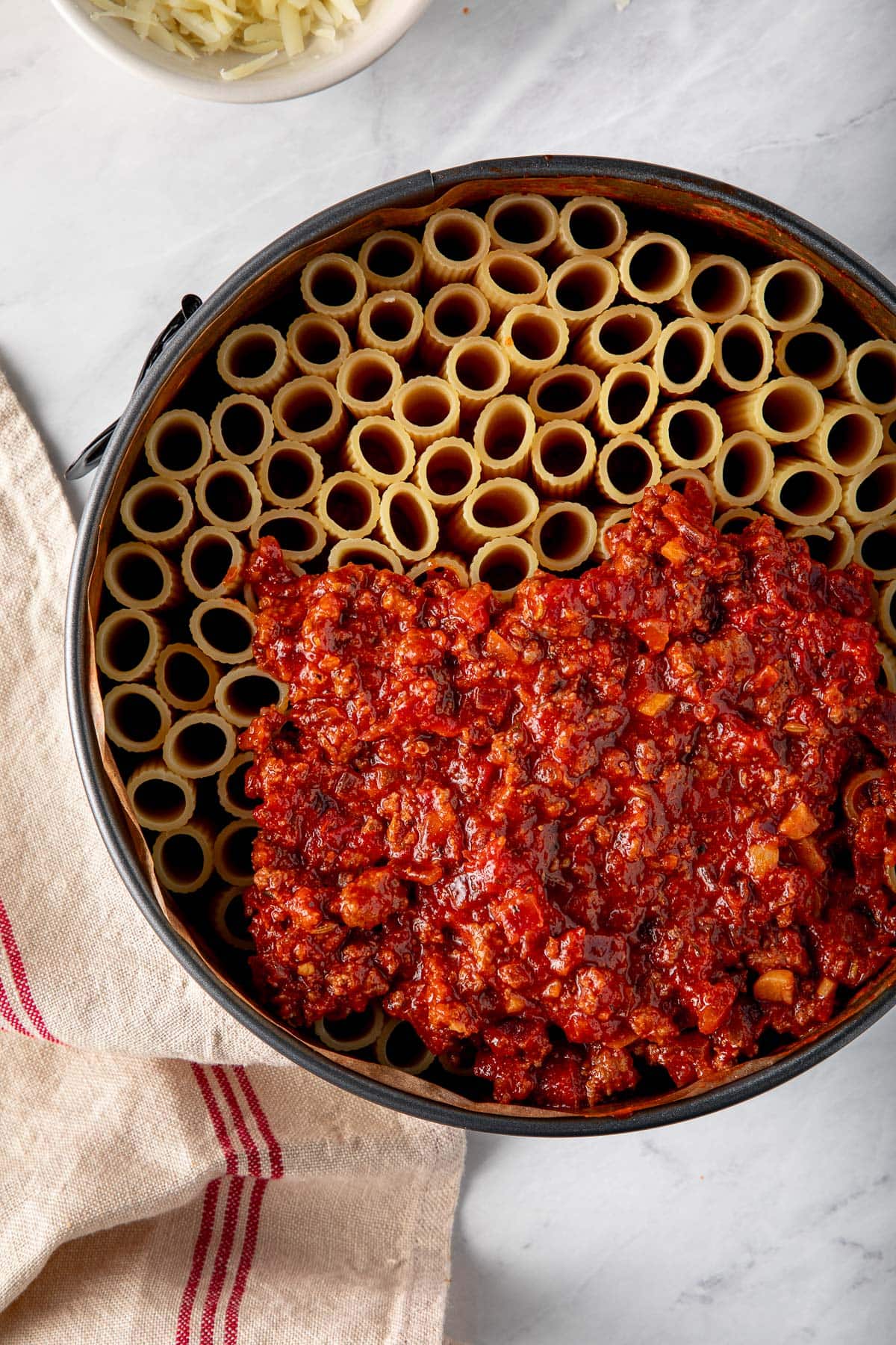 springfrom pan with upright rigatoni and tomato meat sauce partially covering the top.