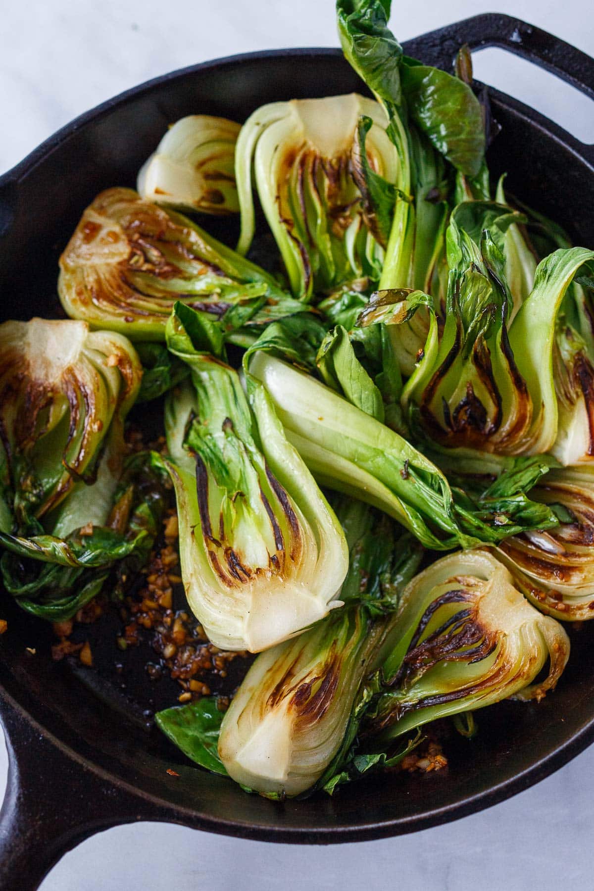 combining the bok choy with the garlic and the sauce.