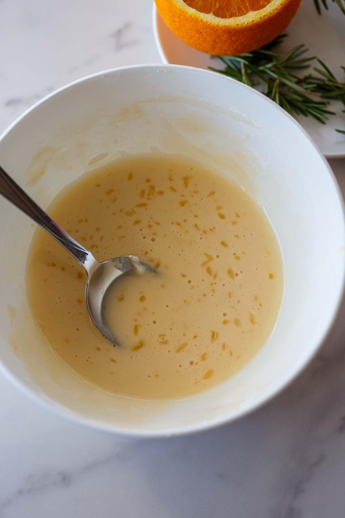 Glaze mixed up in a white bowl with a spoon.