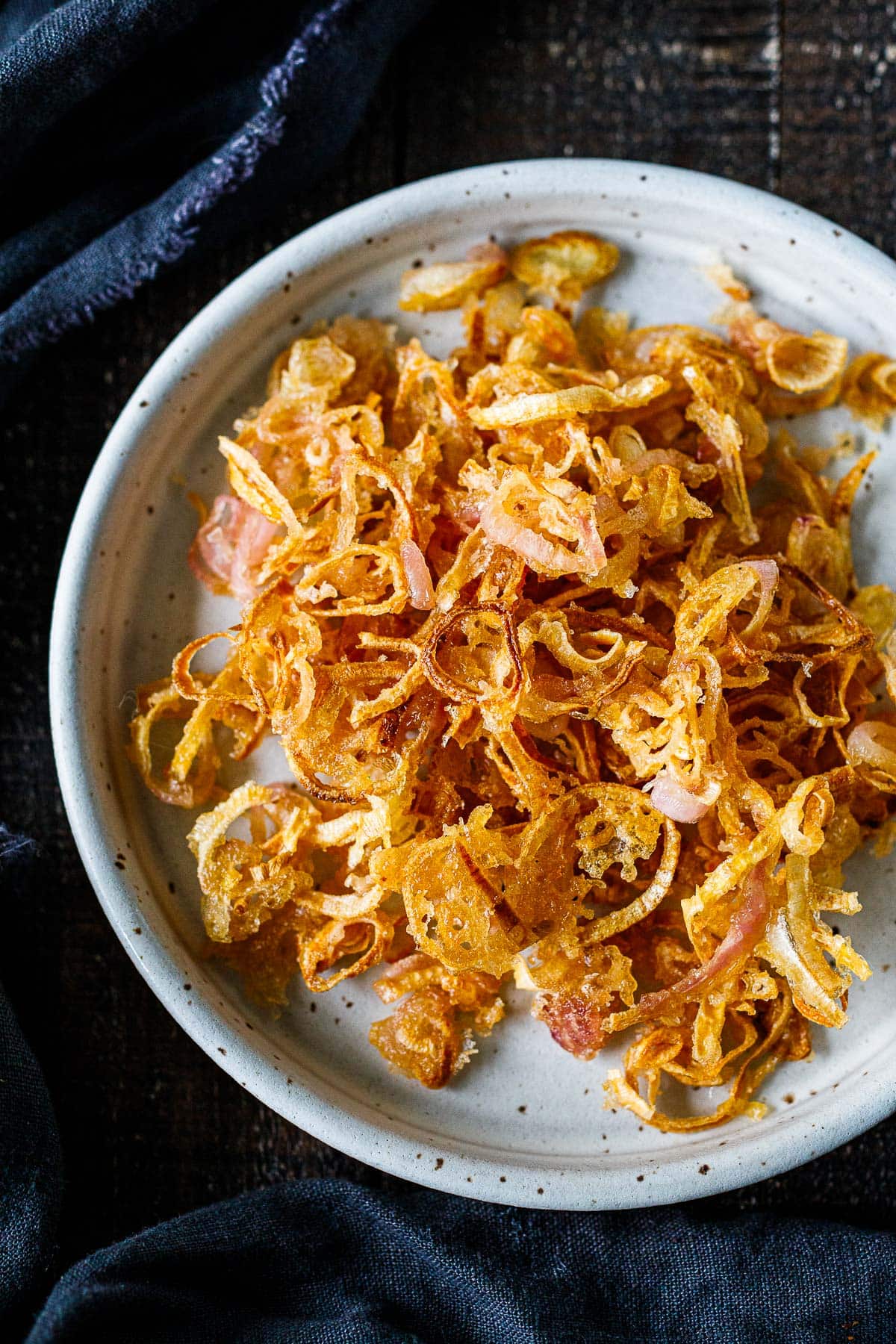 ceramic dish with fried shallots piled on plate.