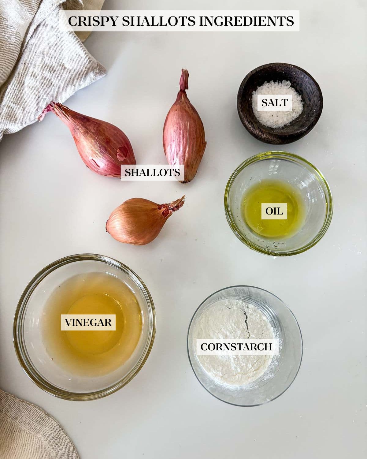 ingredients for crispy shallots - small dishes of salt, vinegar, cornstarch, and oil, next to three shallots. 