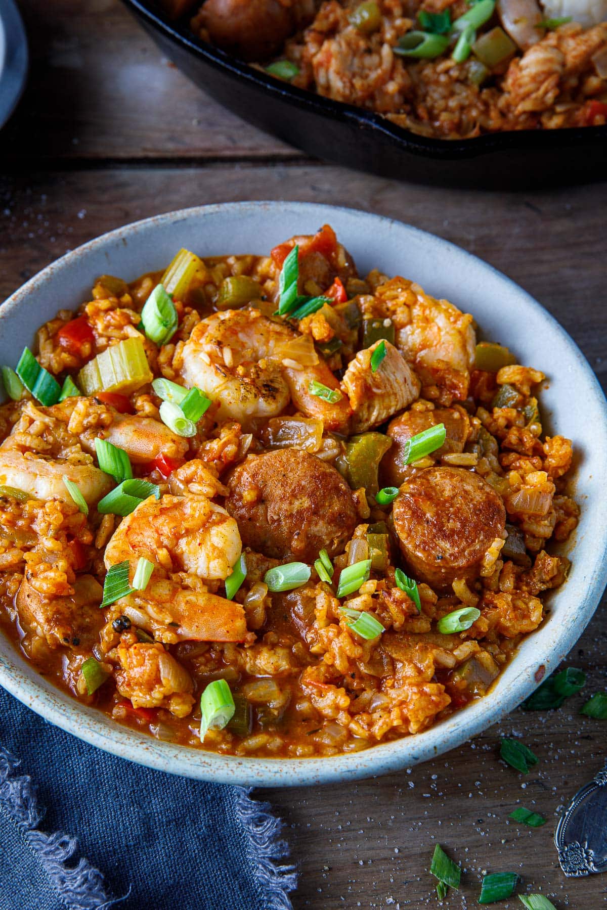 bowl of jambalaya with chicken sausage, shrimp, chicken, and a garnish of green onions.