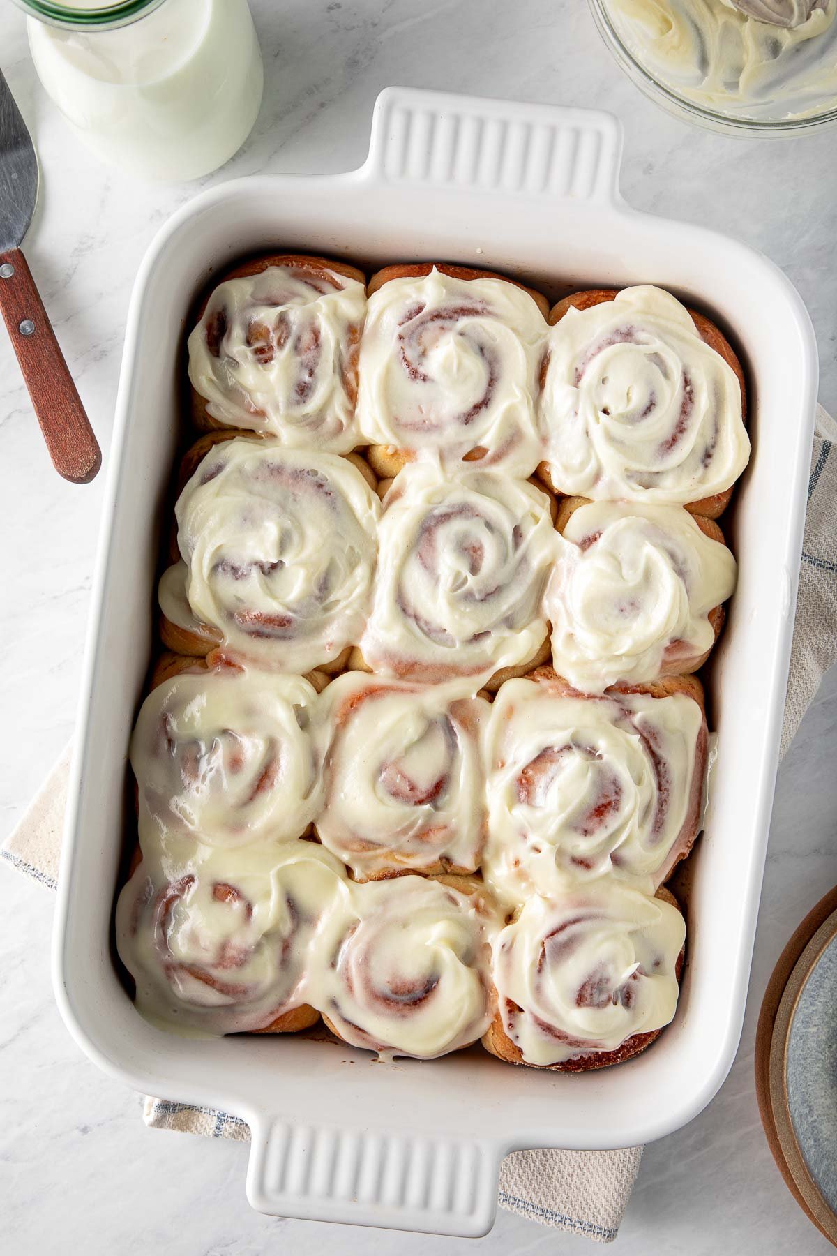 rectangular baking dish with sourdough cinnamon rolls with cream cheese frosting.
