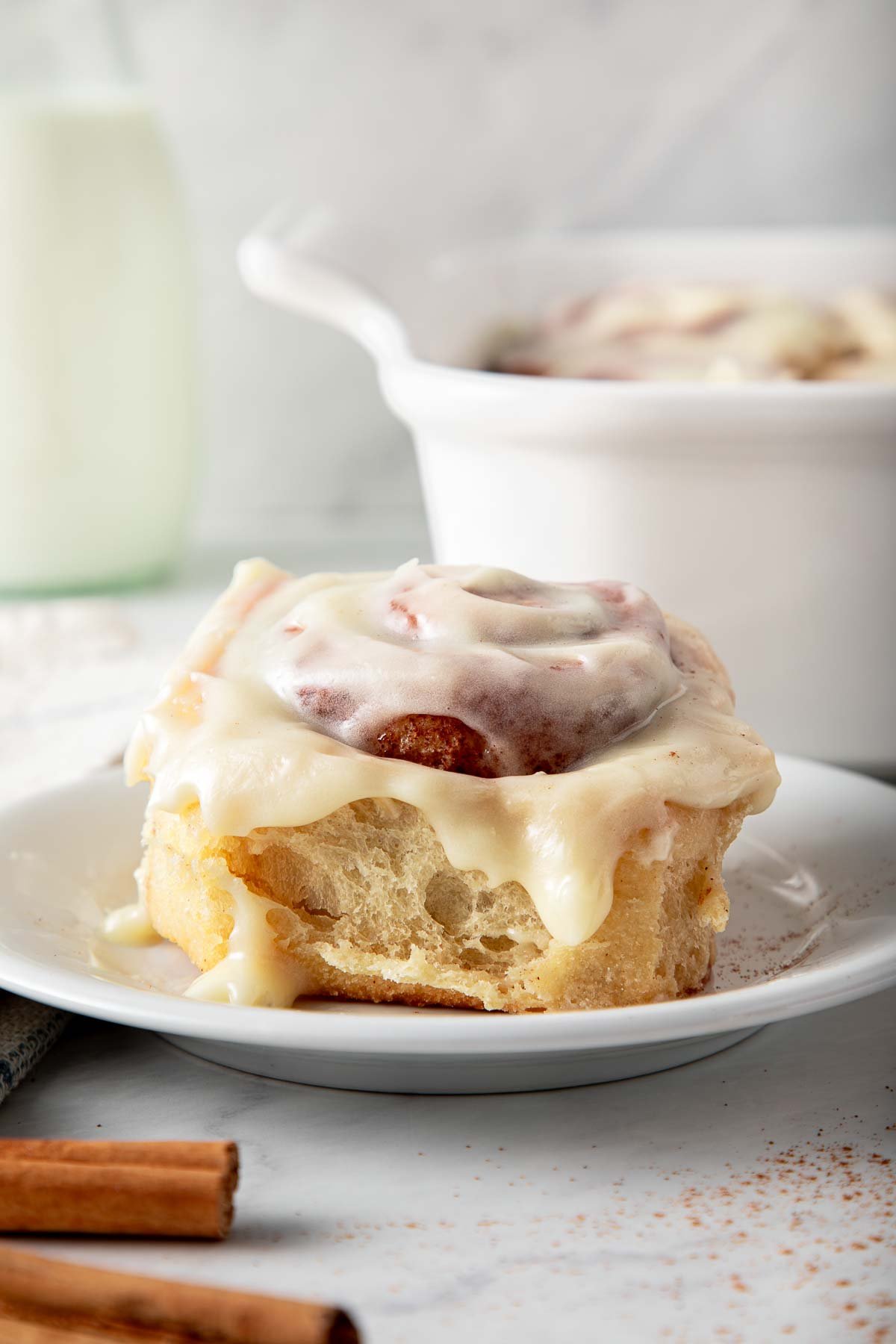 sourdough cinnamon roll on plate with cream cheese frosting.