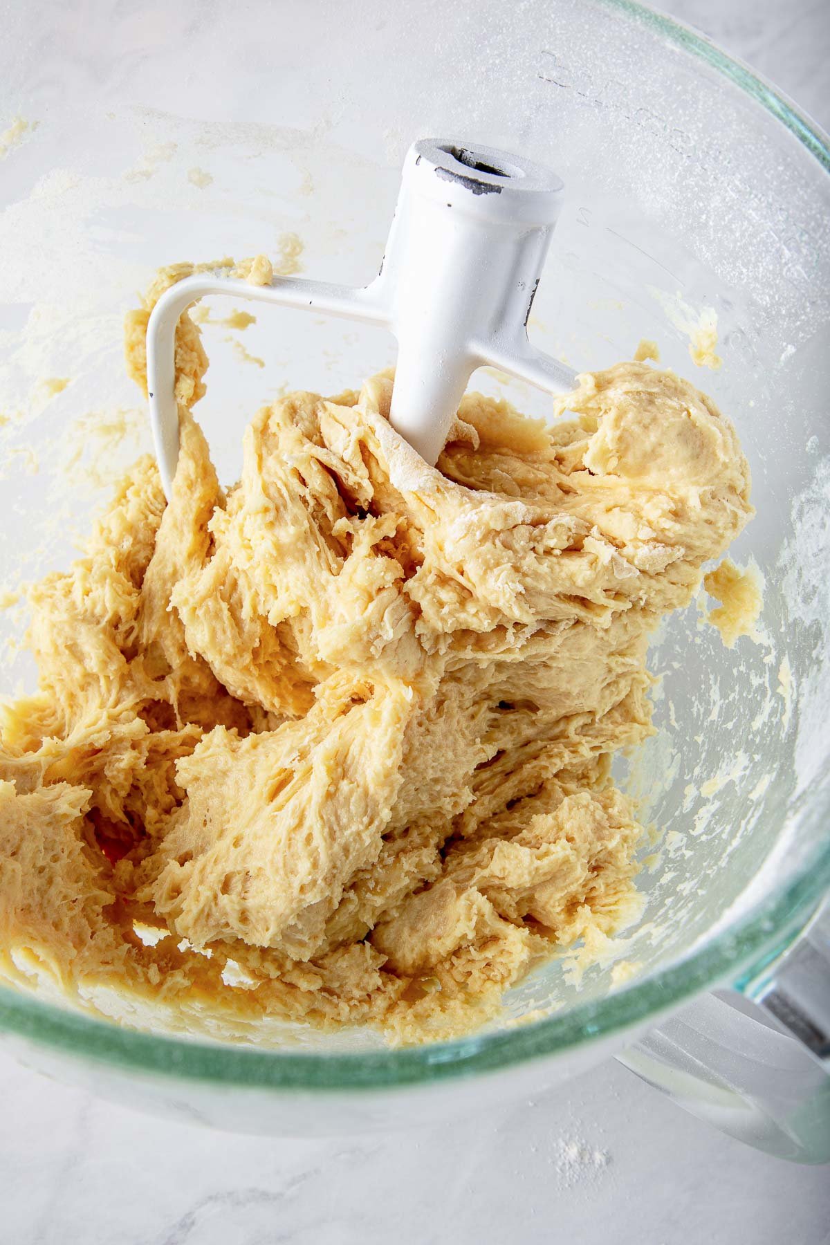 dough hook with sourdough cinnamon roll dough in glass bowl. 