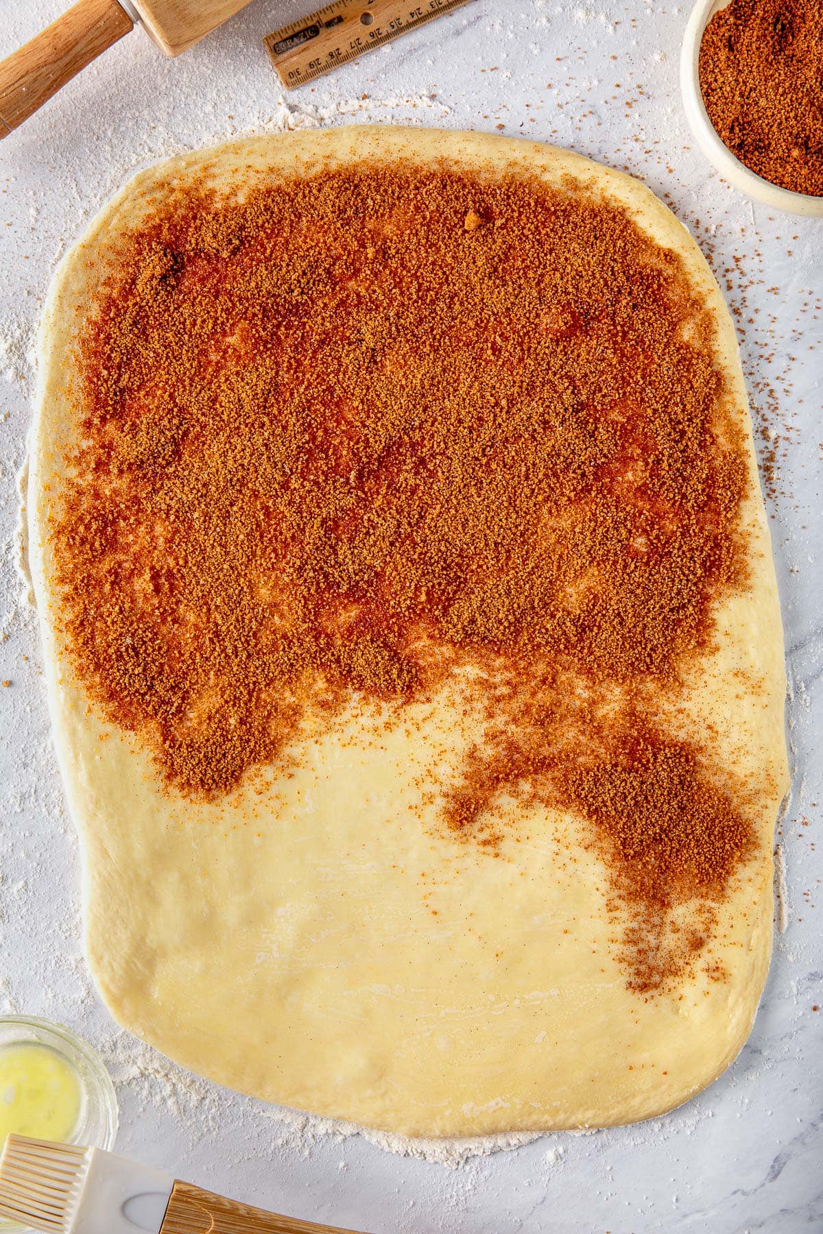 sourdough cinnamon roll dough rolled out with cinnamon sugar filling spread three quarters of the way.