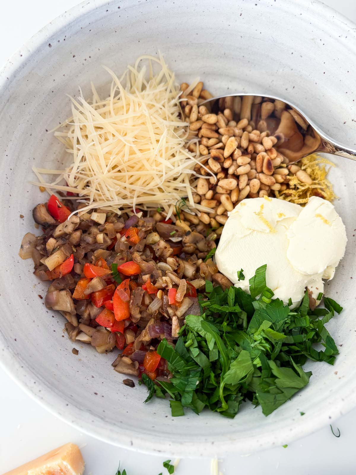 ceramic bowl with sautéed veggies, pecorino, toasted pine nuts, lemon zest, cream cheese, and parsley.
