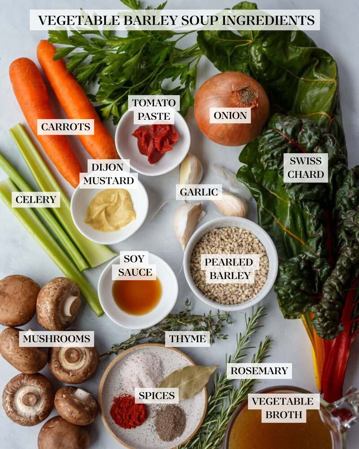 ingredients for vegetable barley soup - carrots, parsley, onion, chard, garlic cloves, celery, mushrooms, thyme, rosemary, measuring cup with broth, small dish of spices, and small bowls of barley, vinegar, Dijon mustard, and tomato paste.