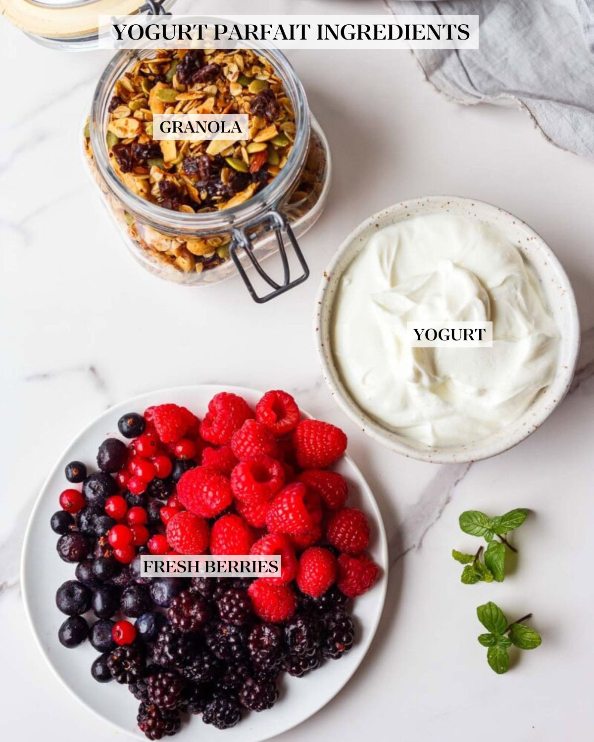 yogurt parfait ingredients labeled - glass jar of granola, bowl of yogurt, and plate of fresh berries. 