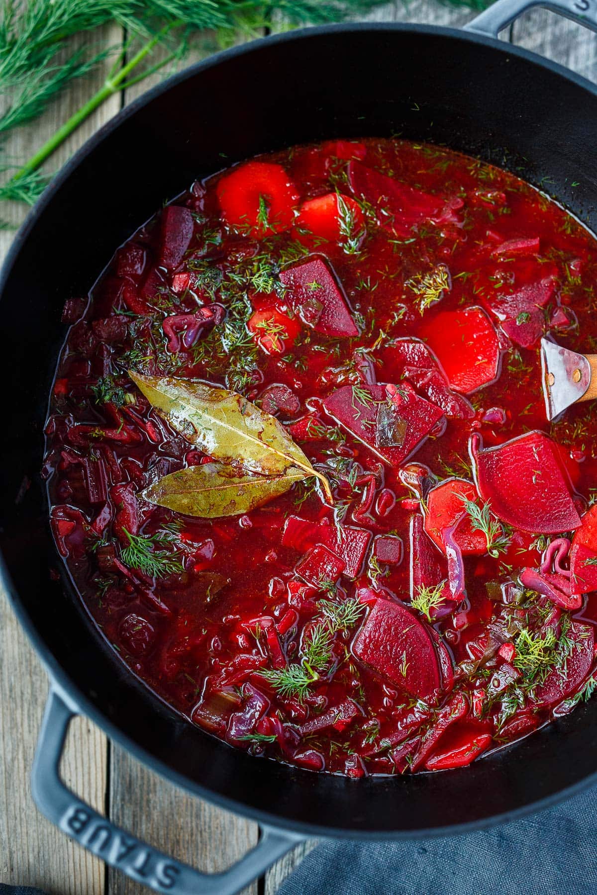 dutch oven with borscht with bay leaves and fresh dill.