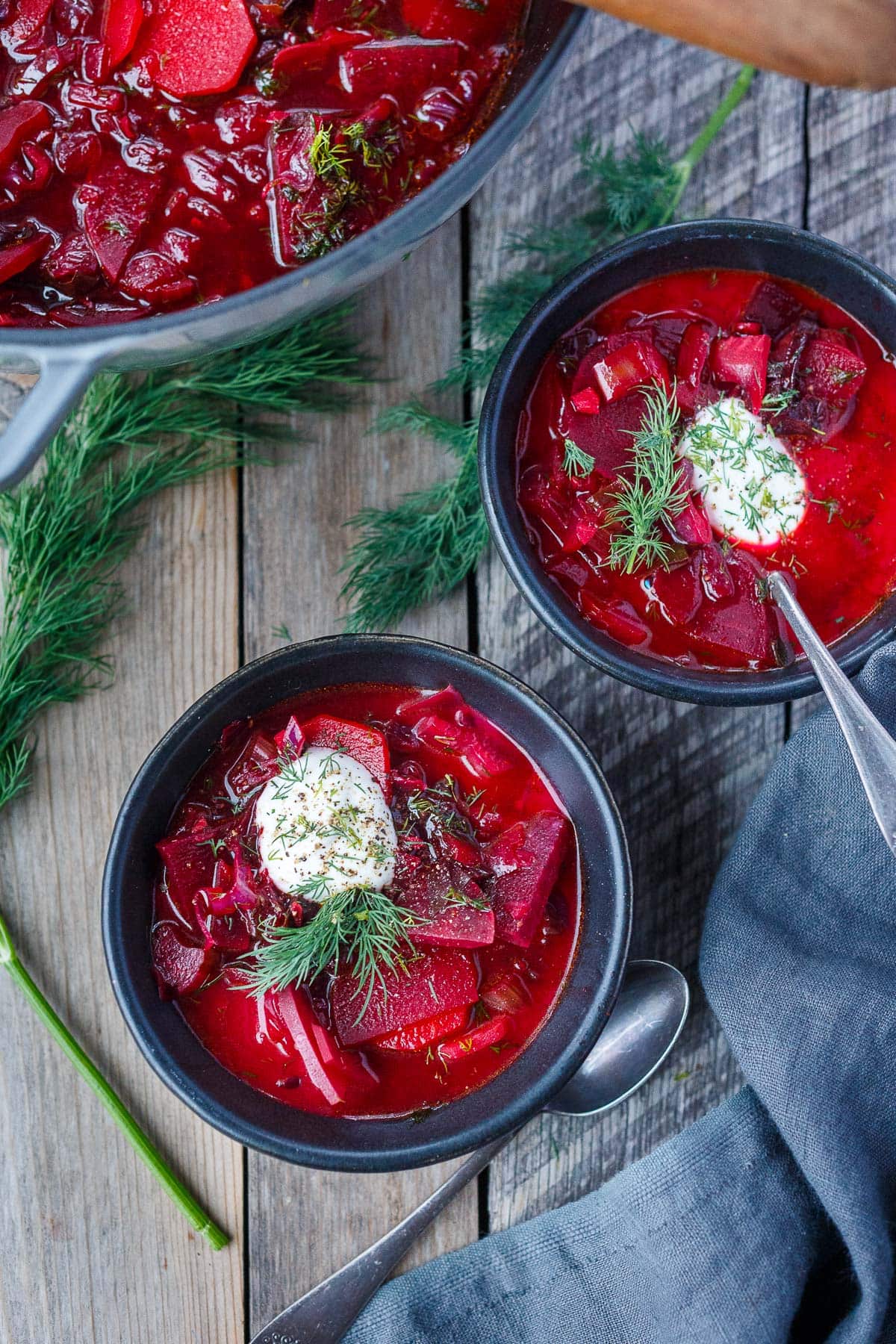 two bowls of beet borscht with dollops of yogurt with fresh dill.