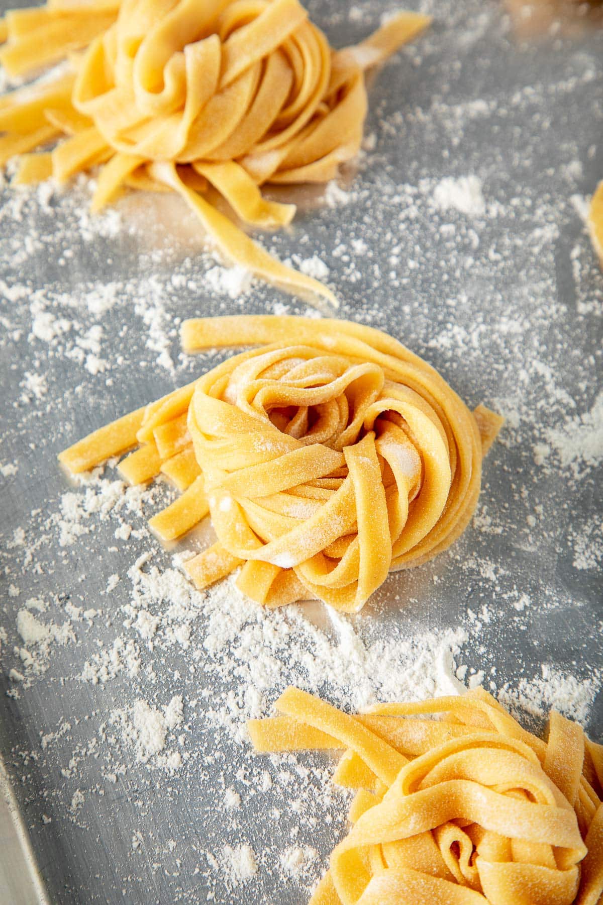 homemade pasta coiled into a nest on flour-dusted baking sheet.