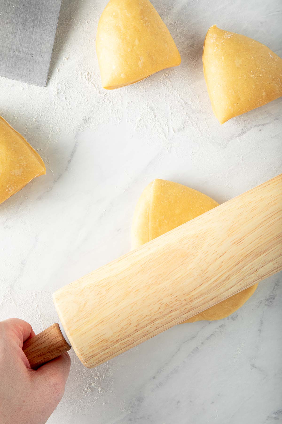wood rolling pin flattening homemade pasta dough ball. 