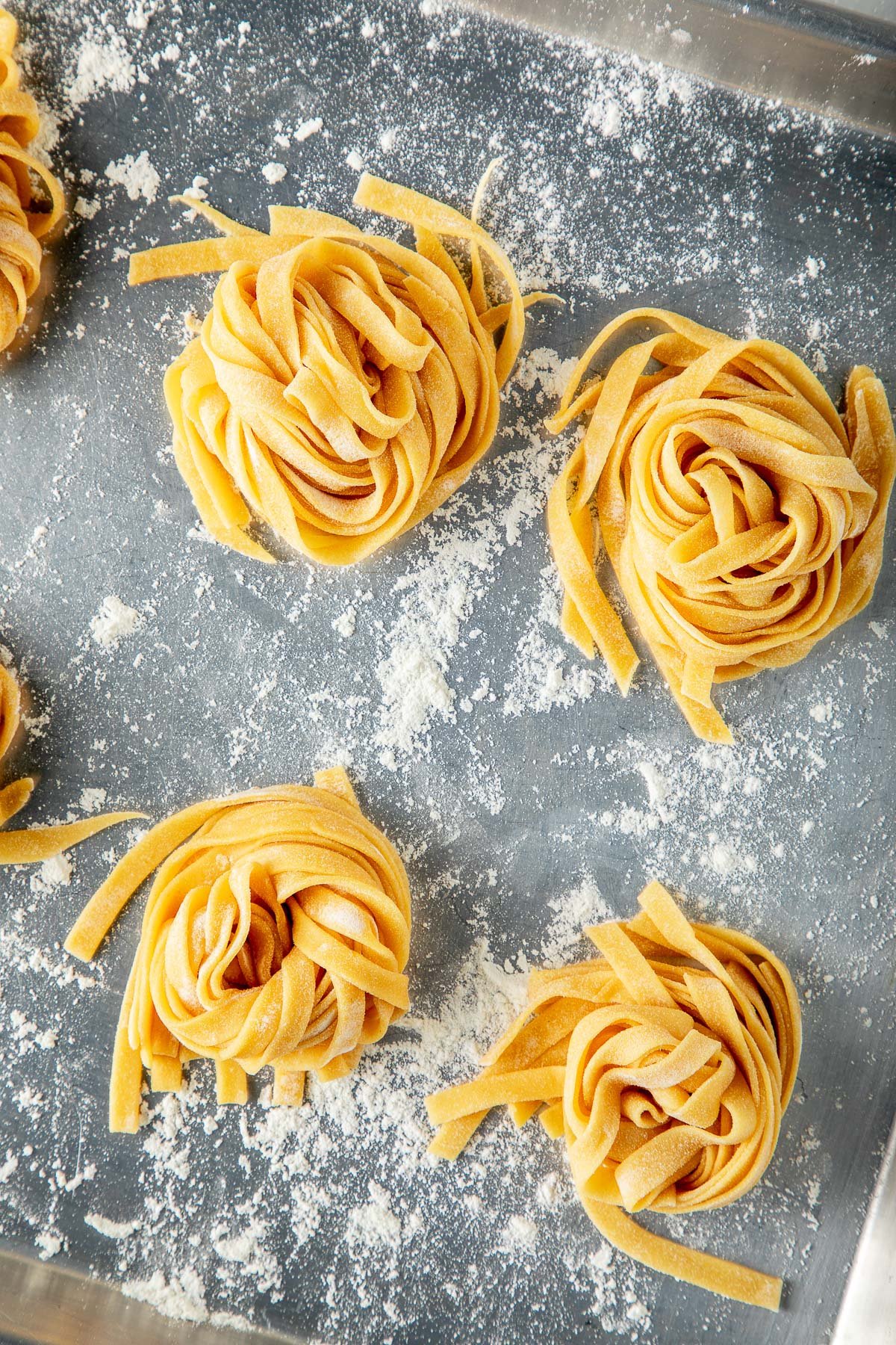 flour-dusted baking sheet with nests of fresh homemade pasta.