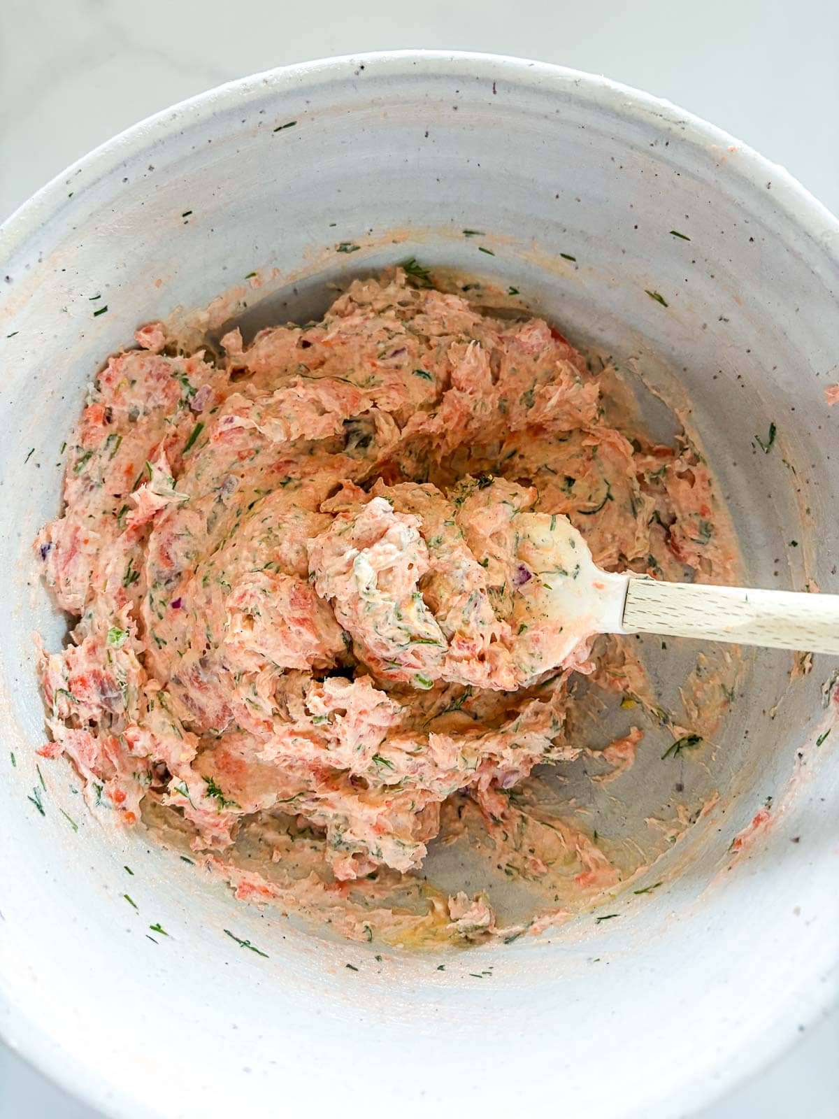 ceramic mixing bowl with smoked salmon dip with spatula. 