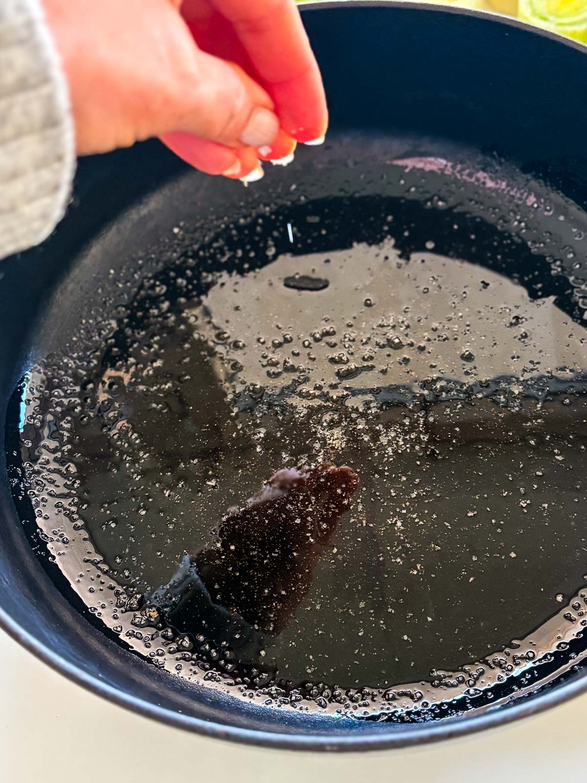 hand sprinkling salt onto cast iron skillet with oil. 