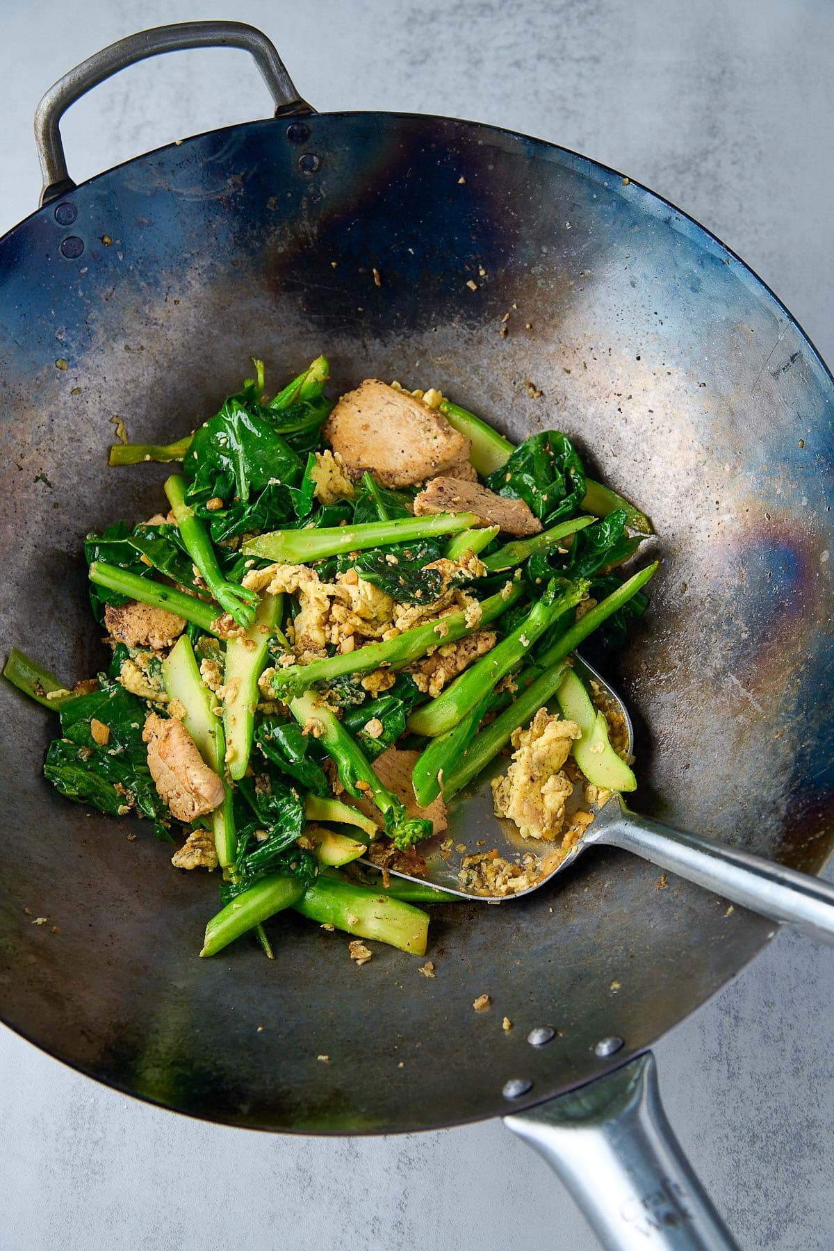stir-frying veggies, chicken, and eggs for pad see ew in wok. 