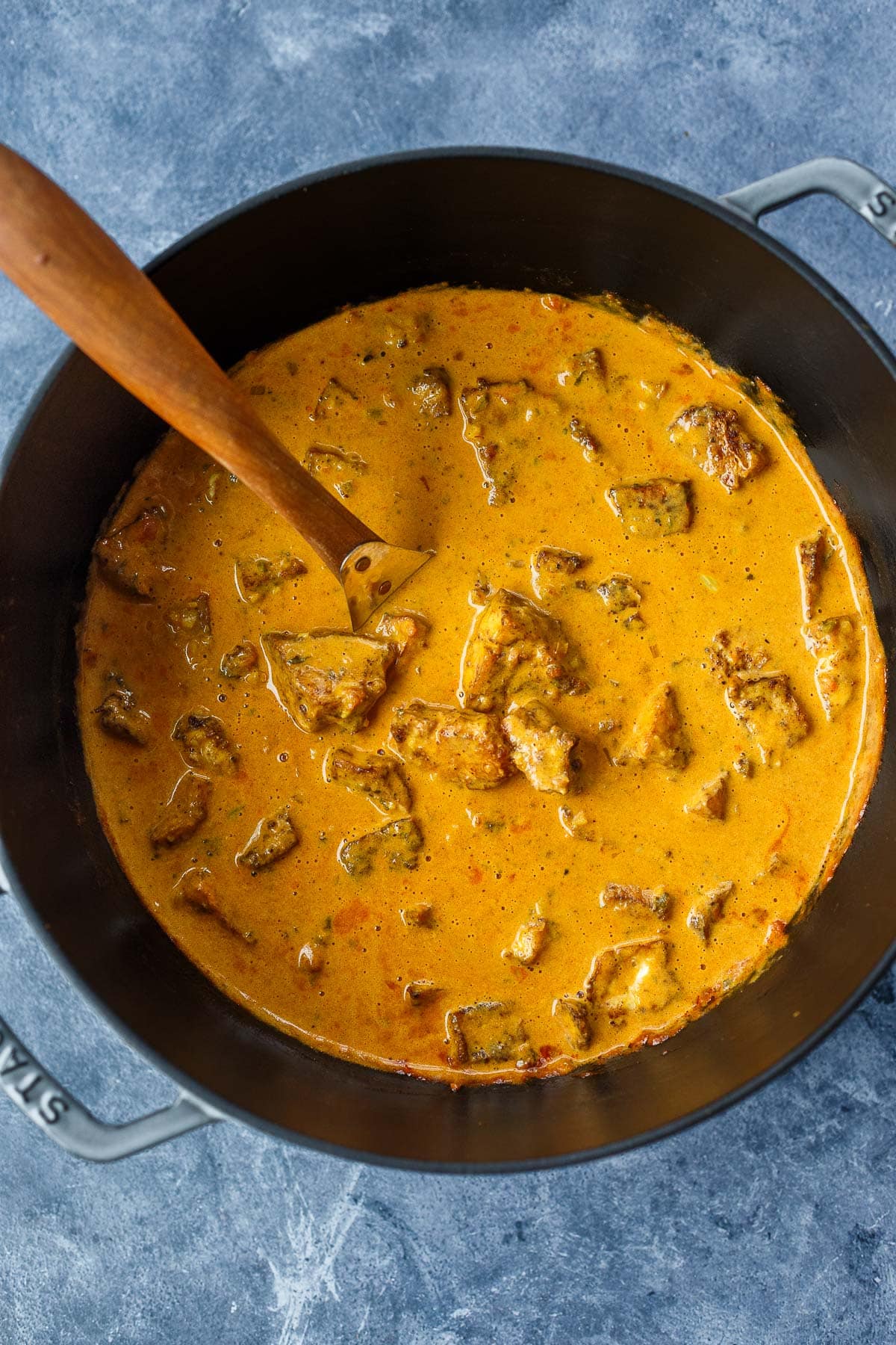 dutch oven with butter tofu, featuring baked tofu in pot of curry sauce.