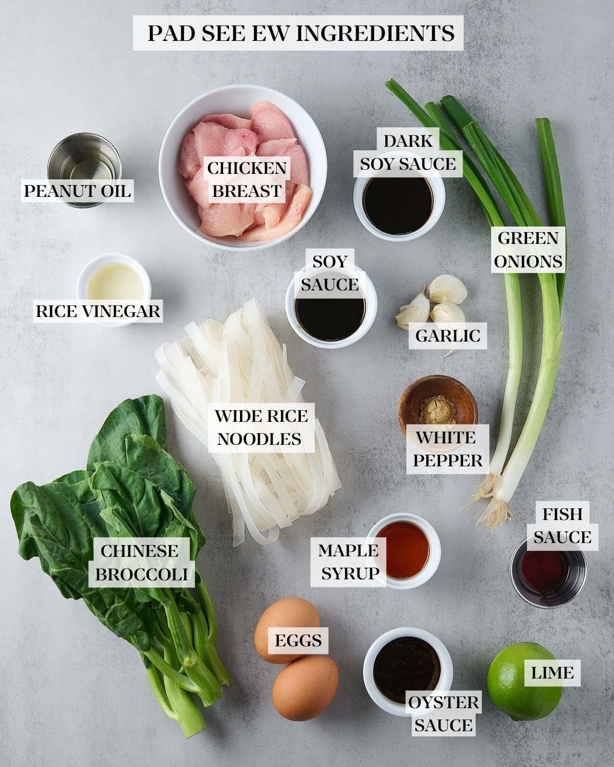 ingredients for pad see ew - bowl of sliced chicken, scallions, garlic cloves, rice noodles, Chinese broccoli, eggs, lime, and small bowls with sauces. 