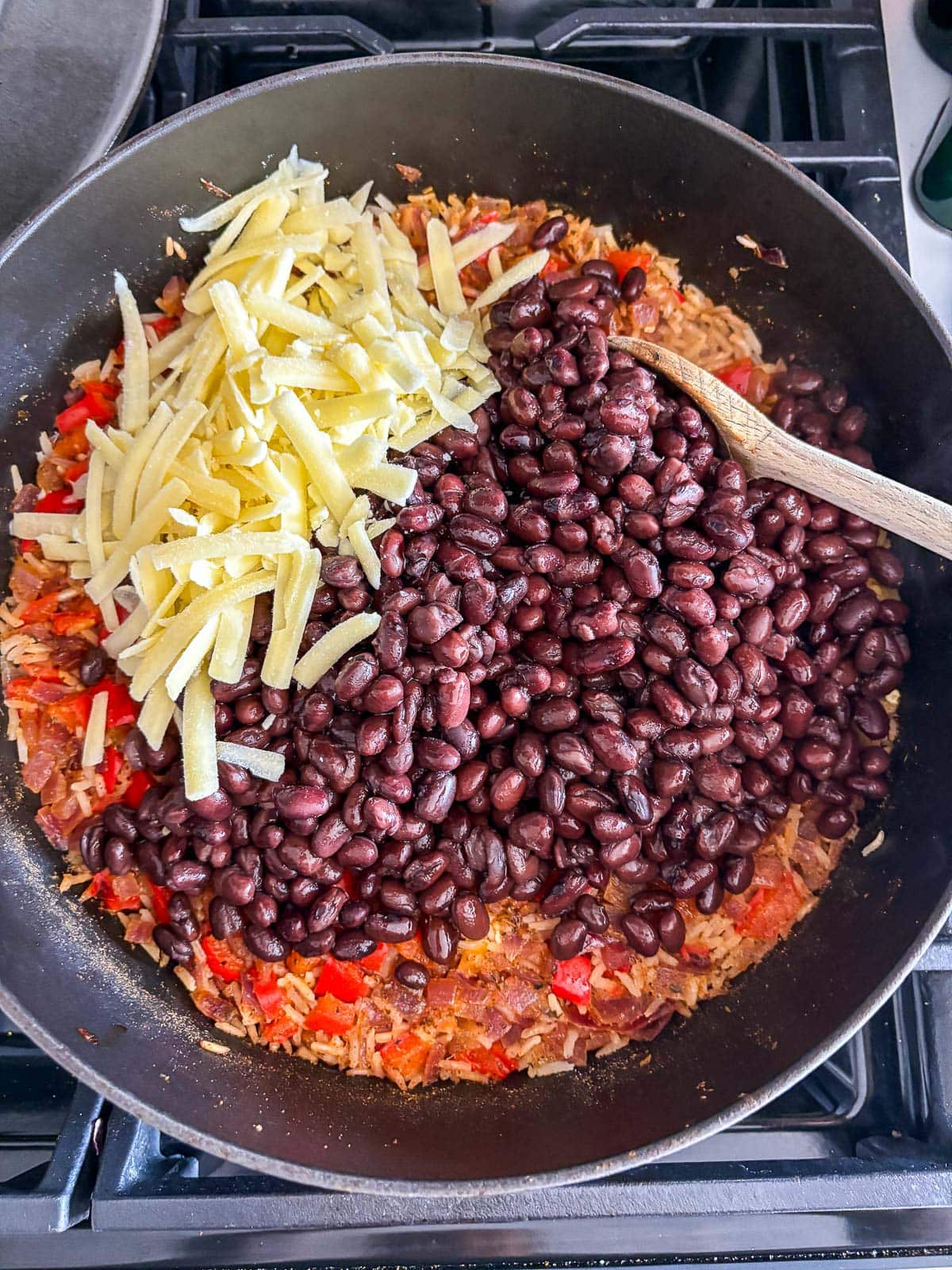 dutch oven with sautéed veggies, rice, broth, and the cheese and black beans added on top.