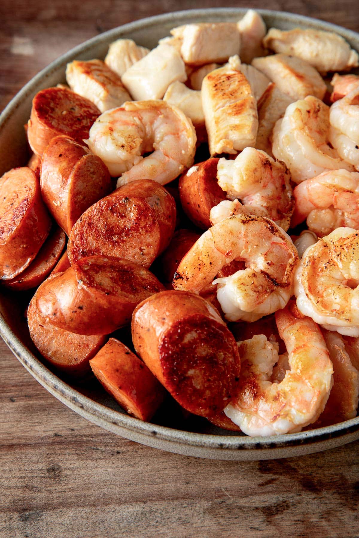 the browned sausage, chicken and shrimp on a plate.