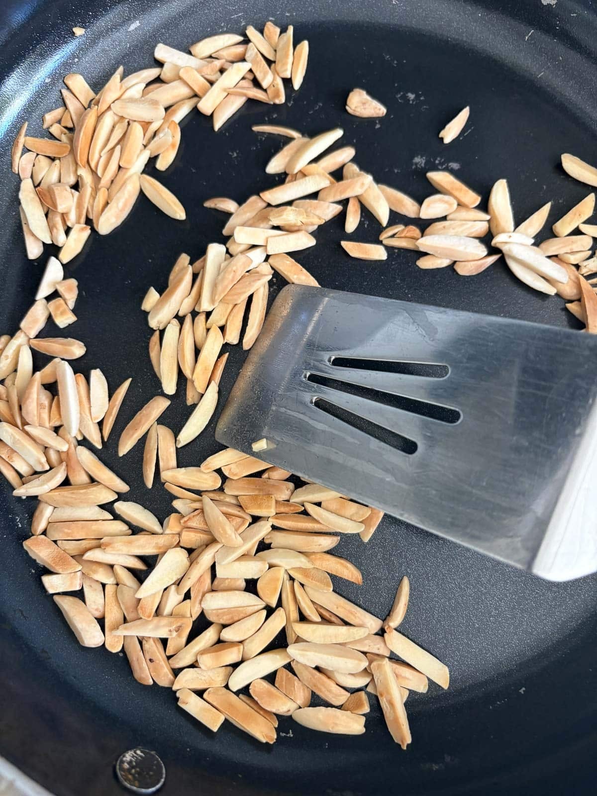toasting slivered almonds in skillet with metal spatula.